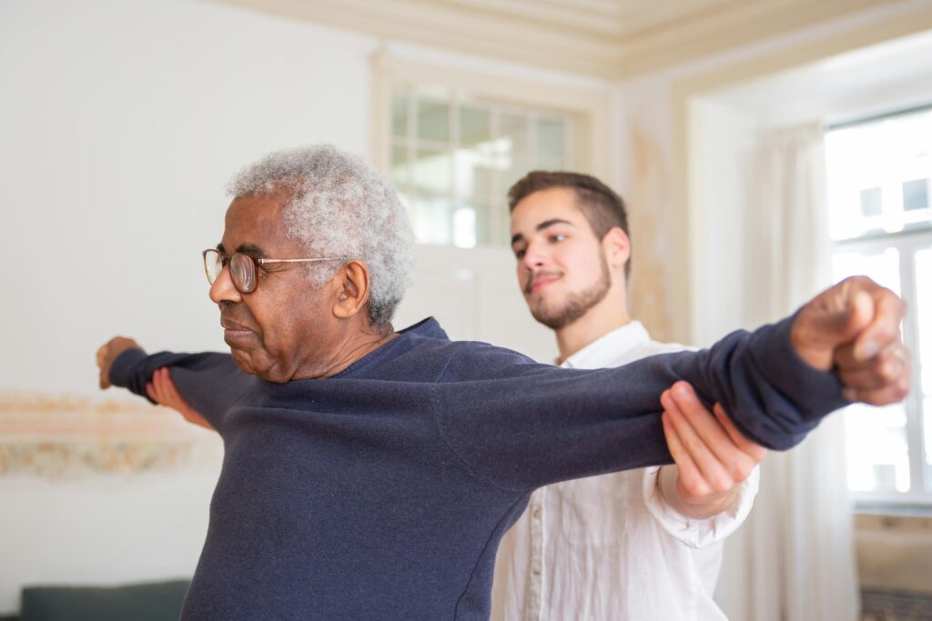 Young attendant doing mobility exercises with senior