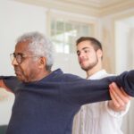 Young attendant doing mobility exercises with senior